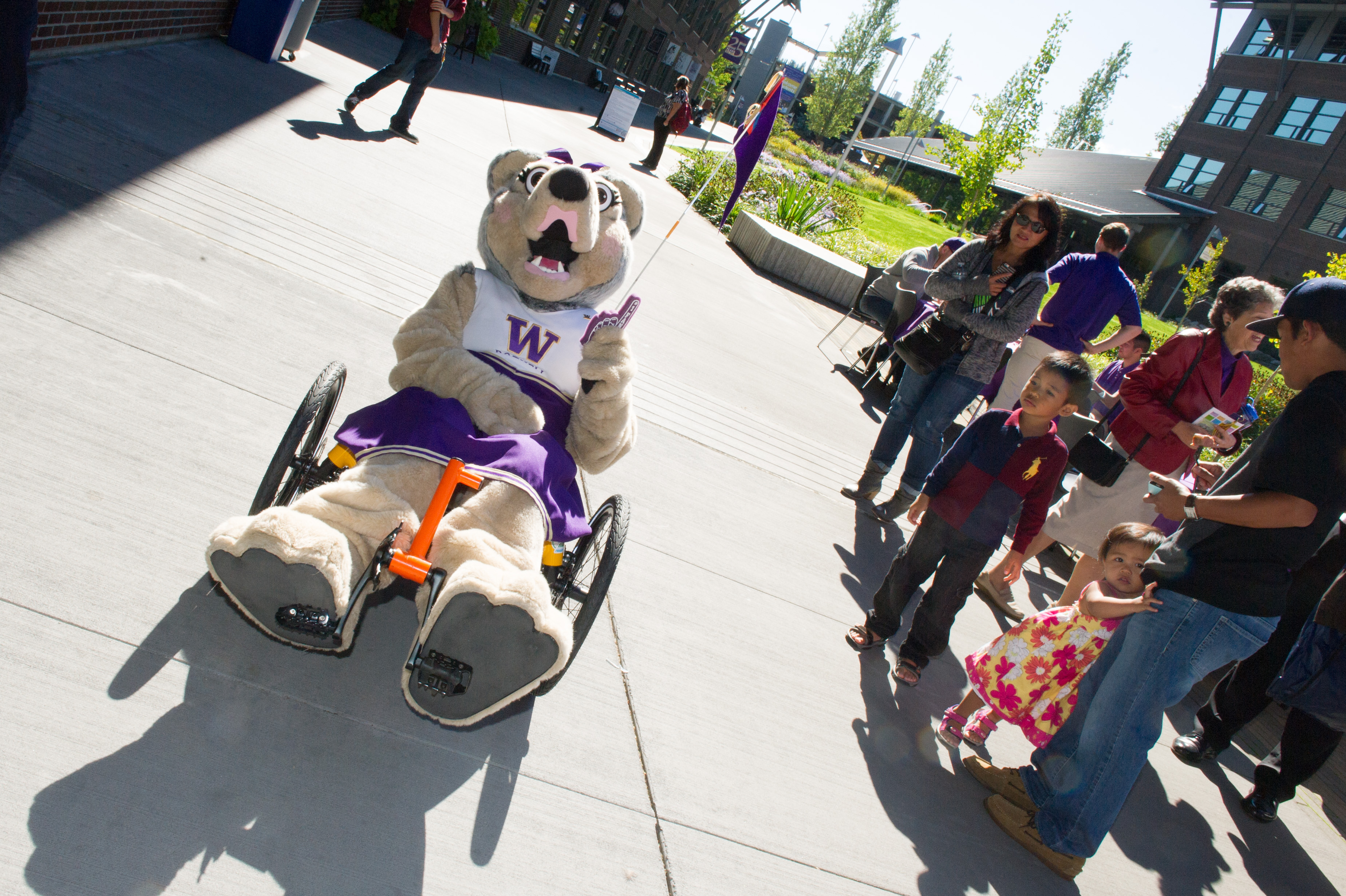 A Husky mascot rides an autonomous trike and gives a thumbs up.